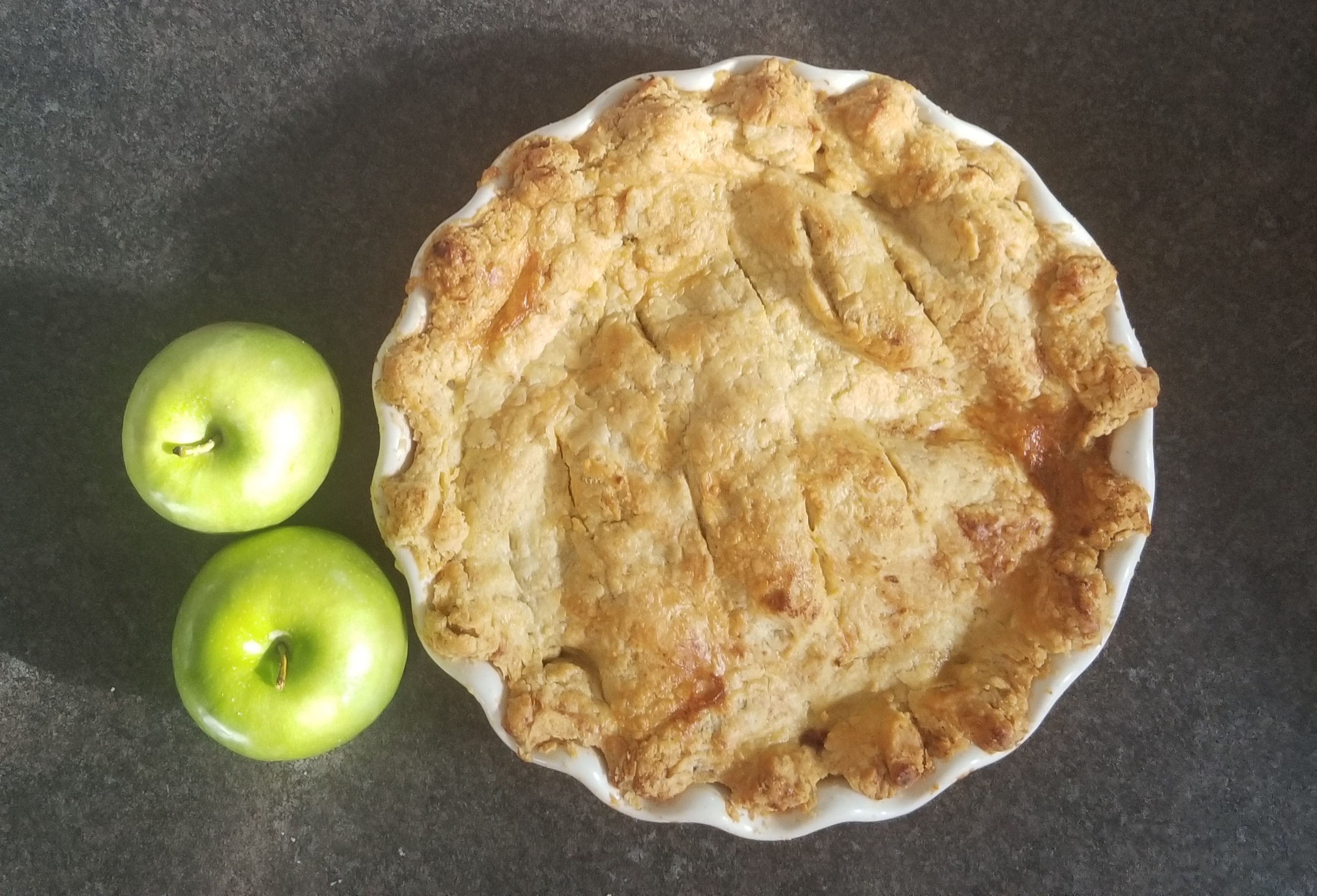 picture of whole baked apple pie and two apples