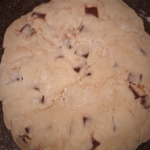 Uncooked chocolate chunk scones in a disc shape.